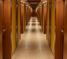 Lange hotelgang met warme houten lambrisering en verlichting, modern en luxueus hotelinterieur.