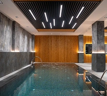 Modern binnenzwembad met sfeervolle verlichting en houten accenten, luxe spa en wellnessfaciliteiten.