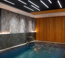 Overdekt hotelzwembad met stijlvolle verlichting en houten afwerking, luxe spa- en wellnessfaciliteiten.