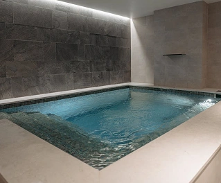 Modern binnenzwembad met minimalistisch design en zachte verlichting, een luxe wellnessfaciliteit.