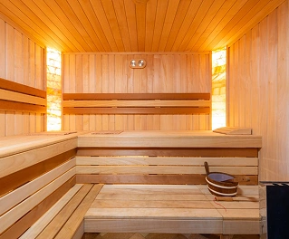 Houten sauna-interieur met banken en warme verlichting, een ontspannende spa- en wellnessomgeving.