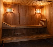 Houten sauna-interieur met banken en sfeervolle verlichting, een ontspannende wellnessruimte ontworpen voor warmtetherapie en ontspanning.